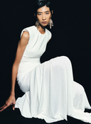 Woman wearing a white dress sitting on a black background