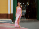Woman in a pink one-shoulder dress walking on a red and white striped platform.